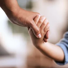 An adult and child holding hands