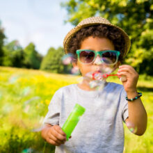 A little boy blowing bubbles in a park in Denver