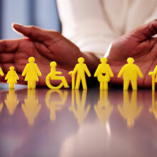 A pair of hands surrounds icons depicting many types of people, people with disabilities and people of different sizes