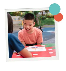 Middle school child who uses a wheelchair reads a book on the playground