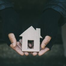 hands hold small cardboard house