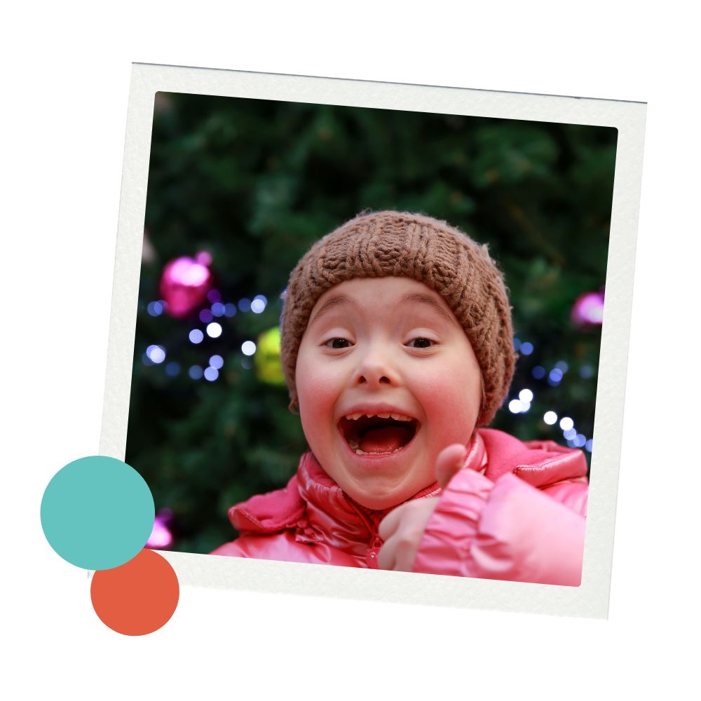 A young girl with Down Syndrome smiles in front of a Christmas tree in Colorado