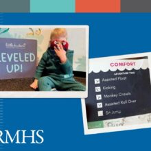 A young boy covers his face with a stuffed animal while he sits next to a sign that says leveled up. Blue graphic background and colored stripe bar at the top. RMHS logo in the corner.